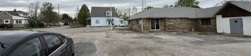Black car is parked in a gravel lot.