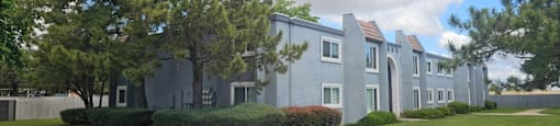 A multifamily housing building with trees in front.