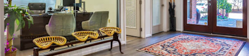A leasing office with a bench, chairs, and a rug at The Inverness Apartments in Houston, TX