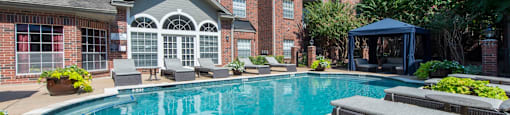 A swimming pool with lounge chairs at The Inverness Apartments in Houston, TX