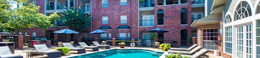 A swimming pool with an apartment building in the background at The Inverness Apartments in Houston, TX