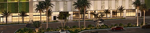 A modern building with a white facade and palm trees in front.