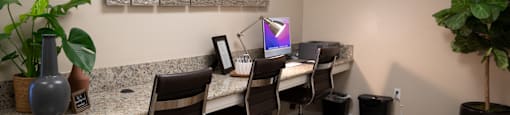 A room with a desk, chairs, and a computer monitor.