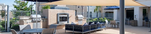A patio with a  table and chairs under a blue and a beige umbrella.