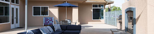 A blue couch is on a patio with a blue umbrella.