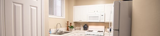A white kitchen with a refrigerator on the right.