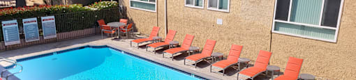 A pool surrounded by orange chairs.