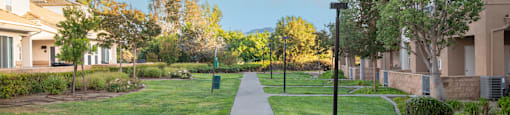 A walkway in a park with grass on either side.