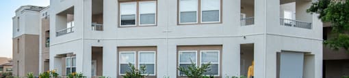 A large, modern apartment building with a pond in front.