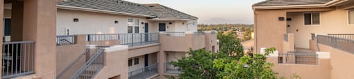 Apartment complex with balconies and trees in the foreground.