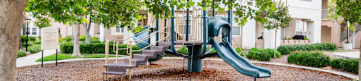 A playground with a green slide and a bench.