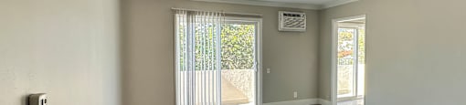 A room with a sliding glass door leading to a balcony.