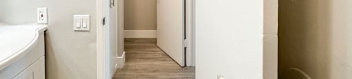 A white door with a silver handle is open to a hallway.
