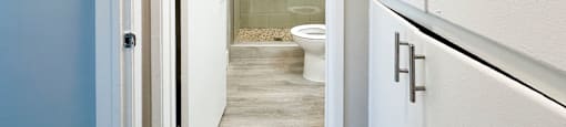 A white door is open to a bathroom with a toilet and a walk-in shower.