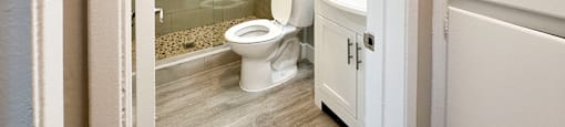 A white toilet is in a bathroom with a walk-in shower.