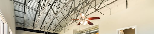 A large empty room with wooden floors and a ceiling fan.