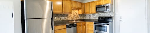 A kitchen with a stainless steel refrigerator and wooden cabinets.