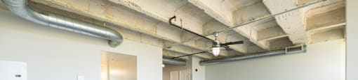 A large empty room with wooden floors and exposed ceiling pipes.