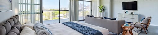A bedroom with a large bed and a balcony overlooking the city.