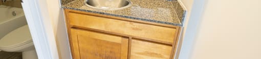 A bathroom with a granite countertop and wooden cabinet.