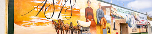 a mural on the side of a building with a horse drawn carriage