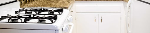 View of kitchen with white cabinets, white appliances and wood look flooring