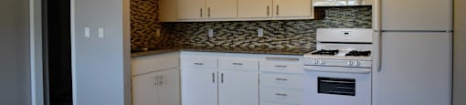 View of kitchen with wood look flooring, white cabinets, white appliances, and tile backsplash