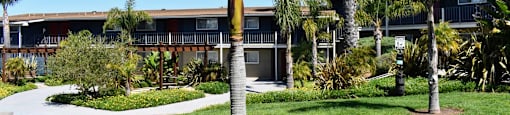 view of building with green grass and tropical landscaping