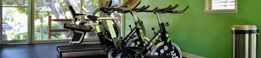 community fitness center with stationary bikes, treadmill, and view outside