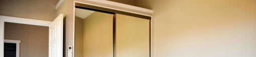 bedroom view of sliding mirror door closet and into hallway, has wood look flooring