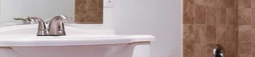bathroom with in laid sink, white cabinets, toilet, and tiled tub shower combo
