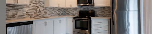 a kitchen with white cabinets and stainless steel appliances