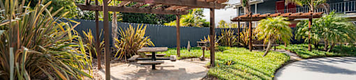 a garden with a picnic table and a pergola