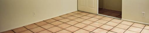 View of bedroom with tile flooring, well lit window, and sliding door closet