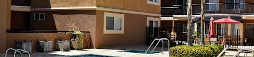 View of fated community pool with spa, exterior buildings and tropical landscaping in the background