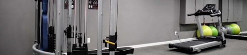 View of community gym featuring weight machines, treadmill, and exercise balls