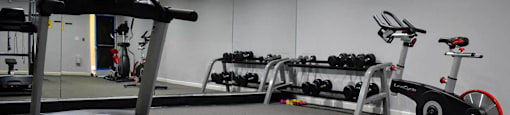 View of community fitness center with treadmill, stationary bike, and free weights