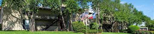 View from the loop of the property with lush grass, flags flying high, and exterior of building in the background