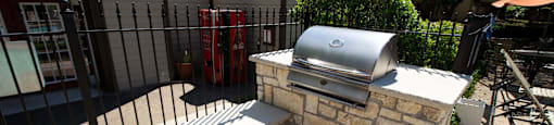 View of grilling station in fenced pool area with counters to prep food
