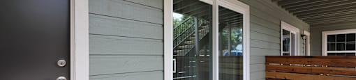 Outside view of front door, sliding glass door to patio, and privacy fence