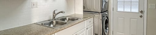 kitchen with granite counters, wood floors, and stacked washer dryer