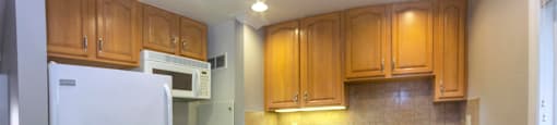 View of kitchen with wood look flooring, white appliances, brown cabinets