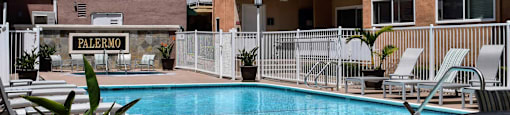 View of gated community pool with lounge chairs and seating with umbrellas