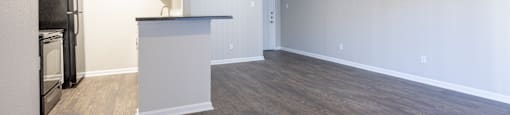 an empty living room with a kitchen and a counter top in the corner