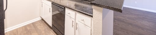a kitchen with white cabinets and a counter top and a sink