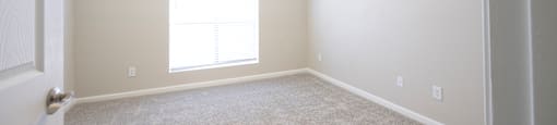 an empty room with carpet and a window