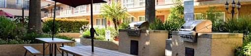 courtyard with grilling station and picnic tables with umbrellas providing shade