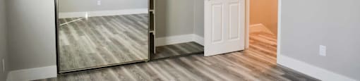 bedroom with wood look flooring, large sliding mirror closet