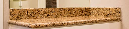 bathroom with stone vanity, large mirror, wood look flooring, and white cabinets