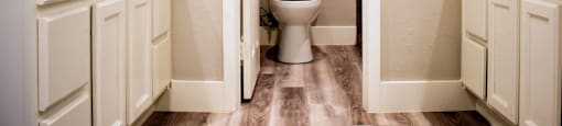 bathroom with wood look flooring, stone counters, white cabinets large mirror, and medicine cabinet.